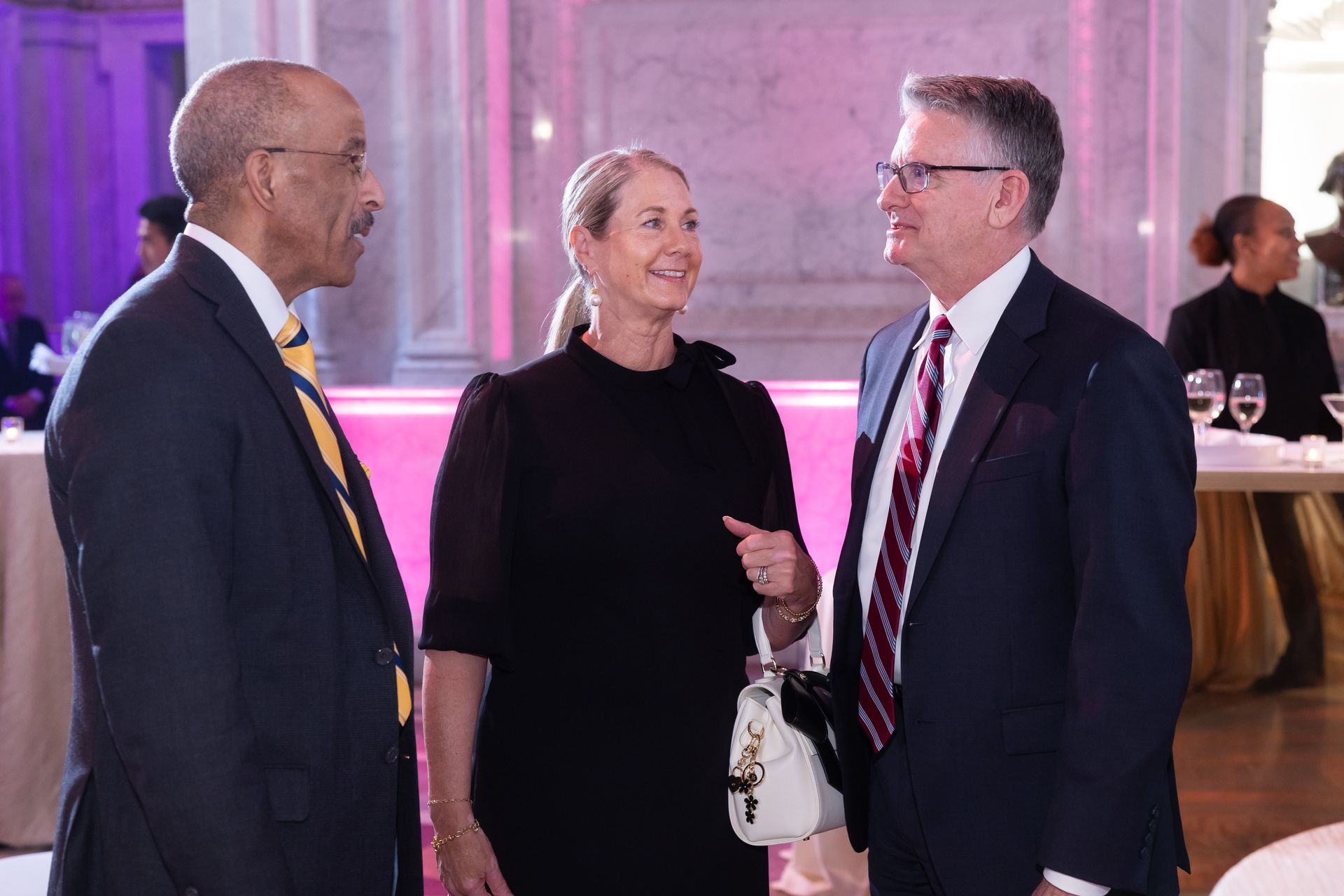 A group of people are standing next to each other and talking in a room.