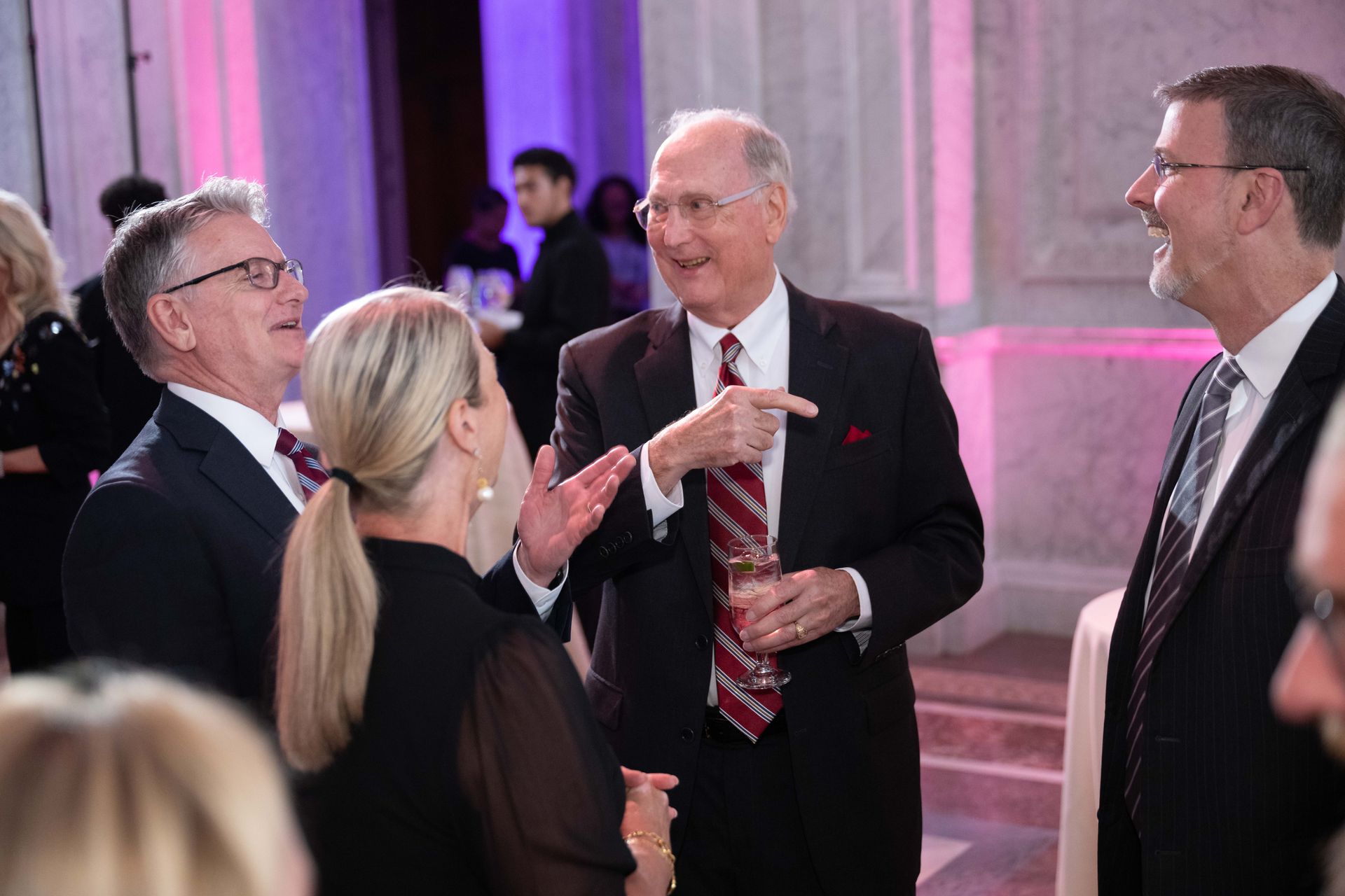 A group of people are standing around talking to each other in a room.