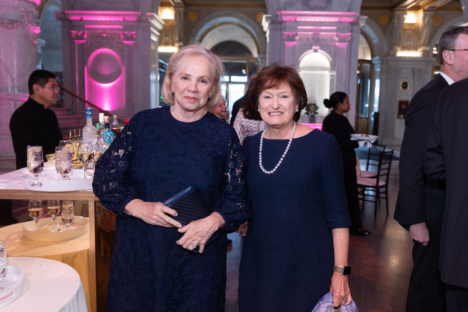 Two women in blue dresses are posing for a picture in a room.