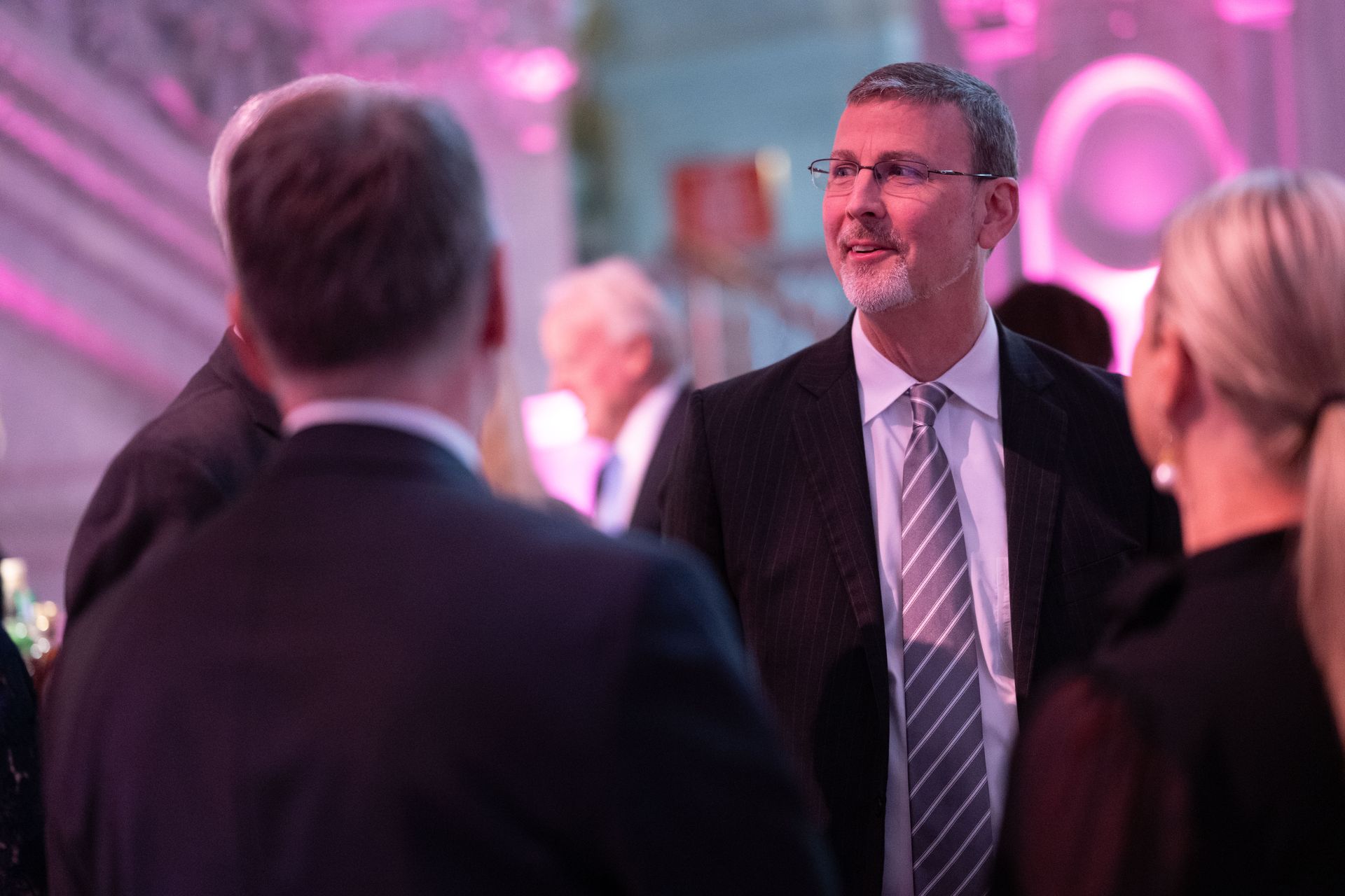 A man in a suit and tie is talking to a group of people.