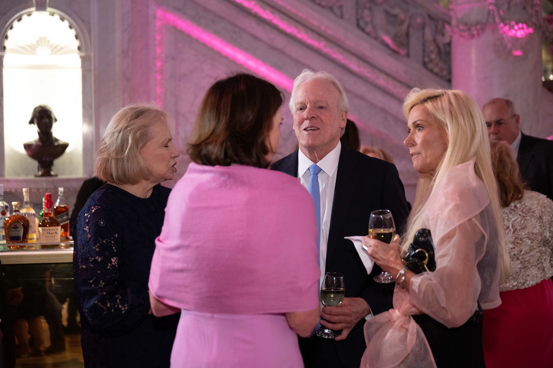 A group of people are standing in a room talking to each other.