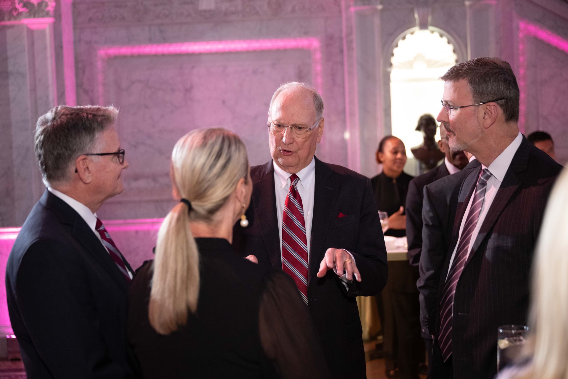 A group of people in suits and ties are talking to each other in a room.