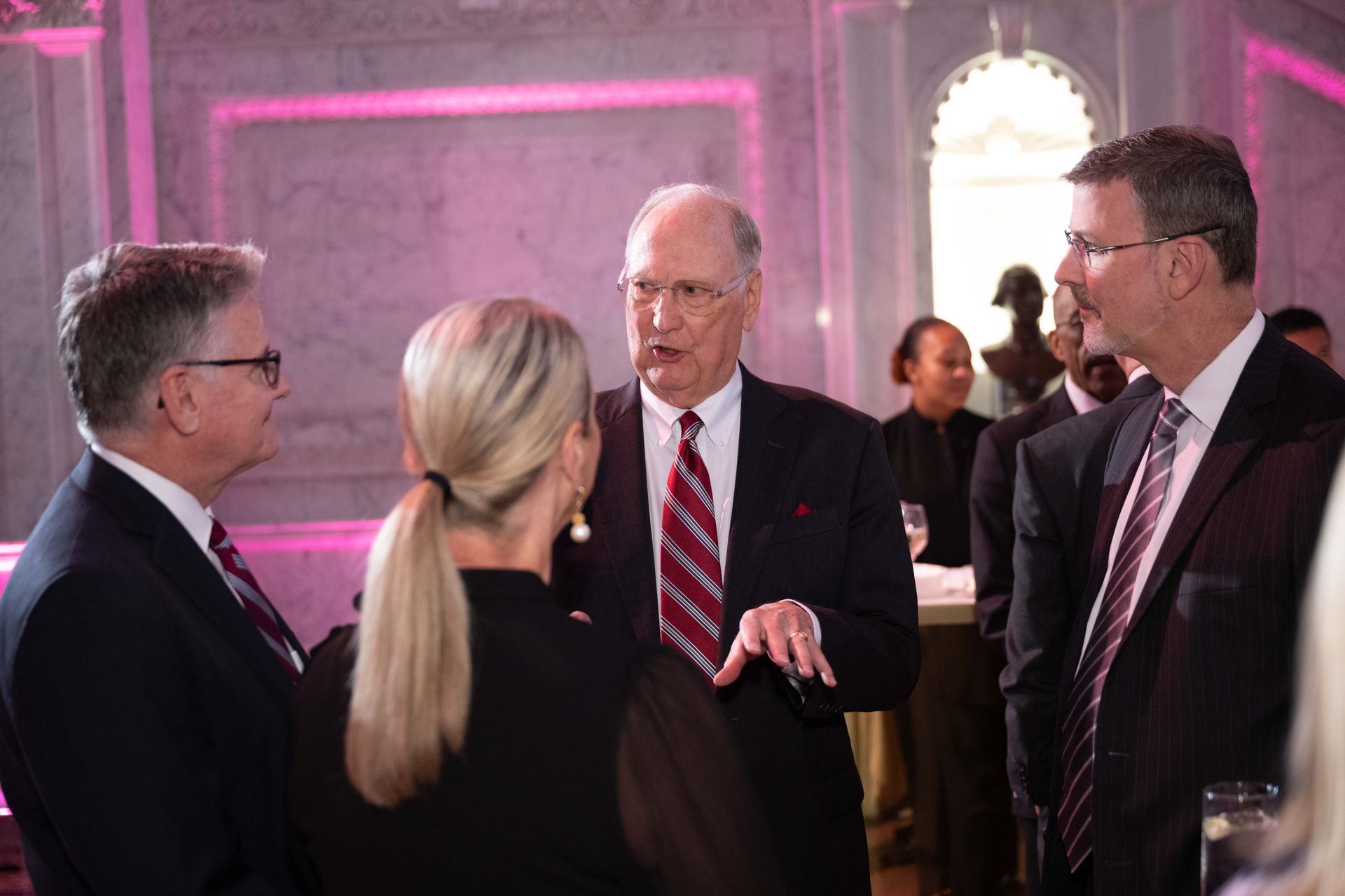 A group of people in suits and ties are talking to each other.