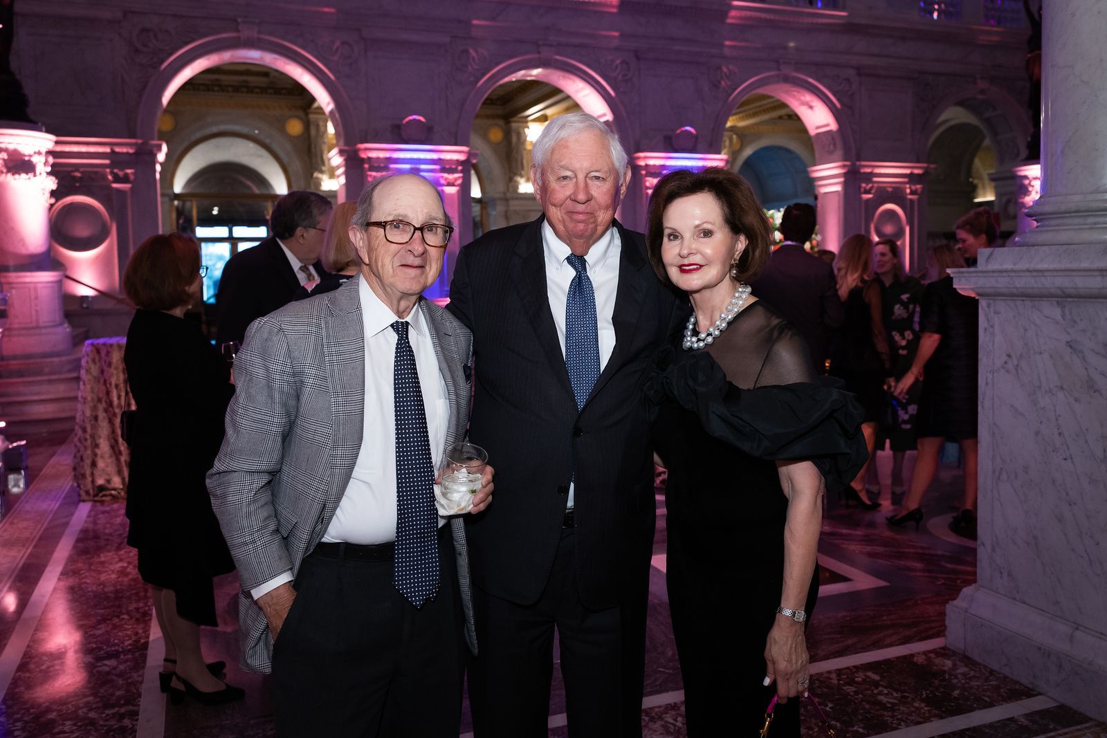 Three people are posing for a picture in a room with arches.