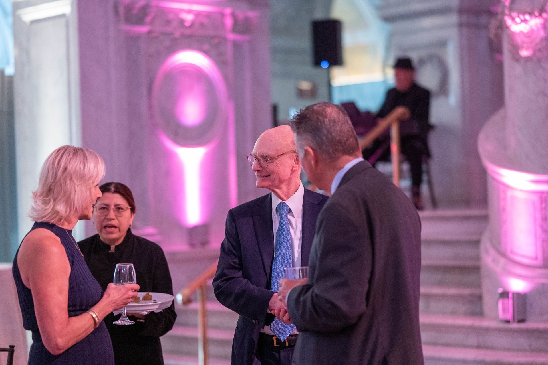 A group of people are standing in a room talking to each other.