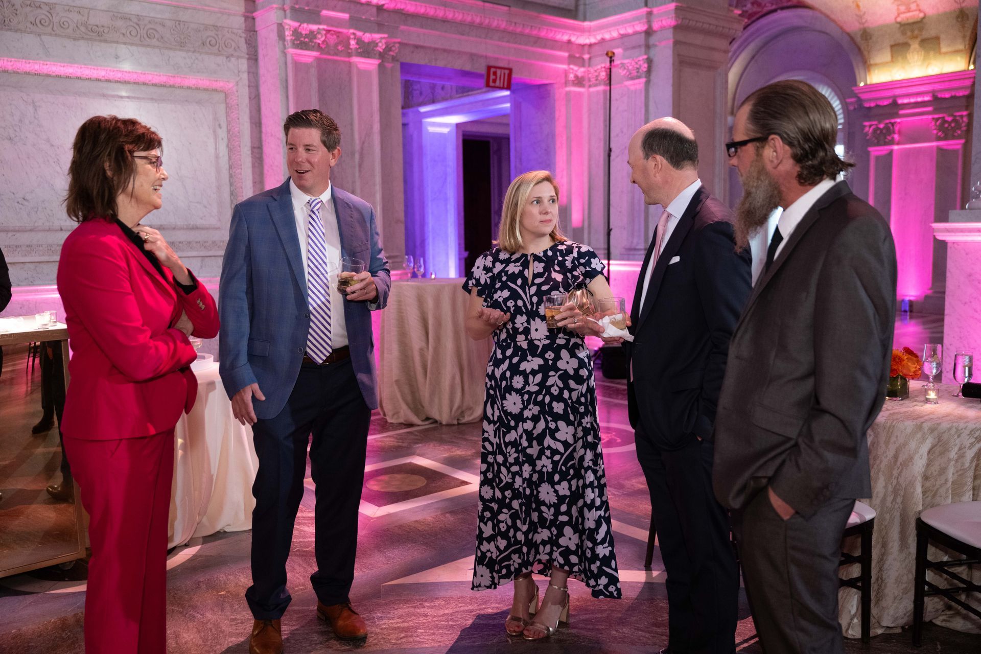 A group of people are standing in a room talking to each other.