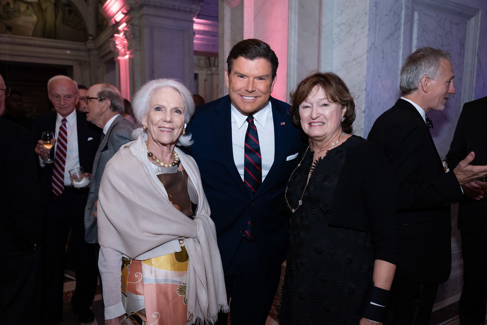 A man in a suit and tie is posing for a picture with two women.