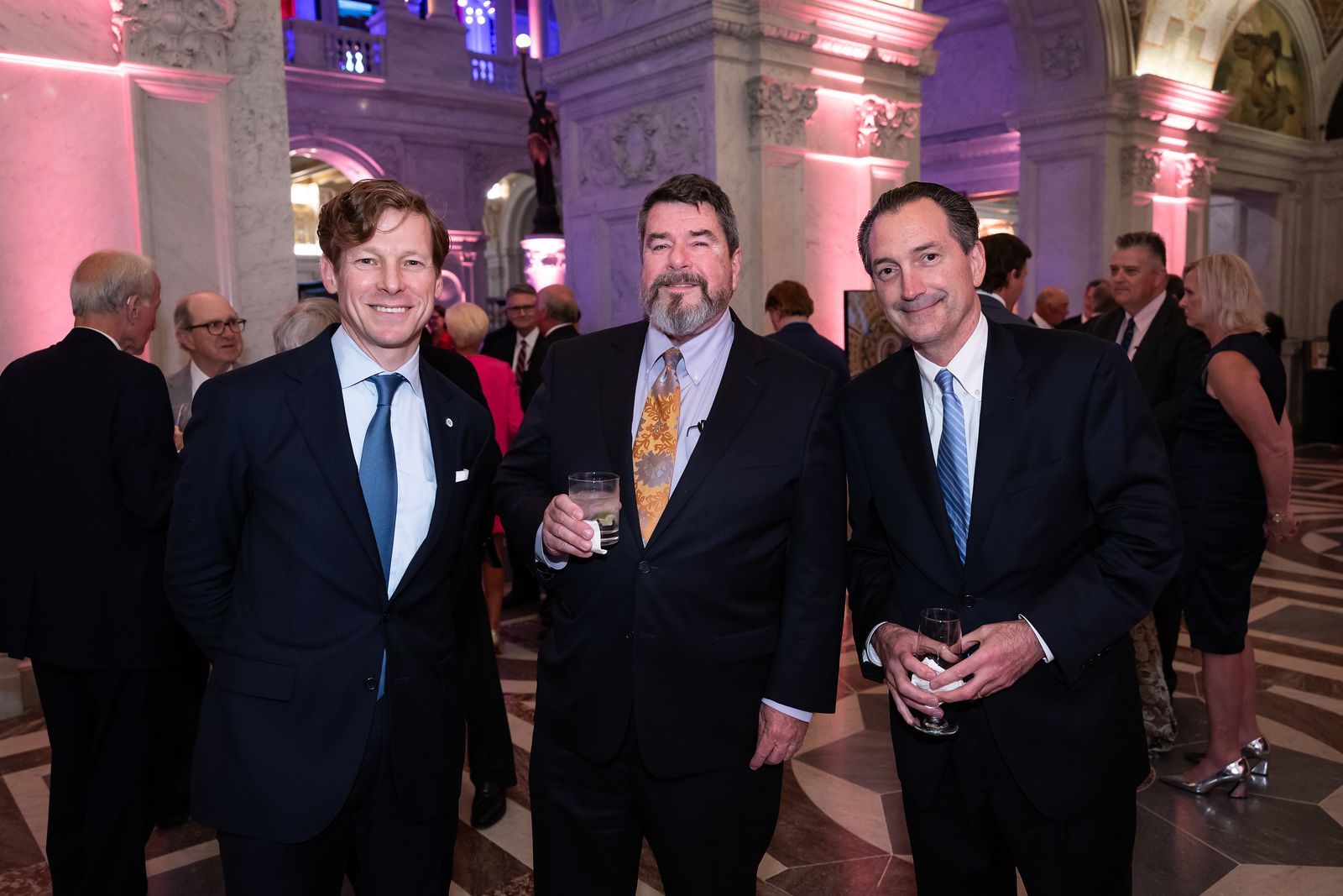 Three men in suits and ties are standing next to each other in a room.