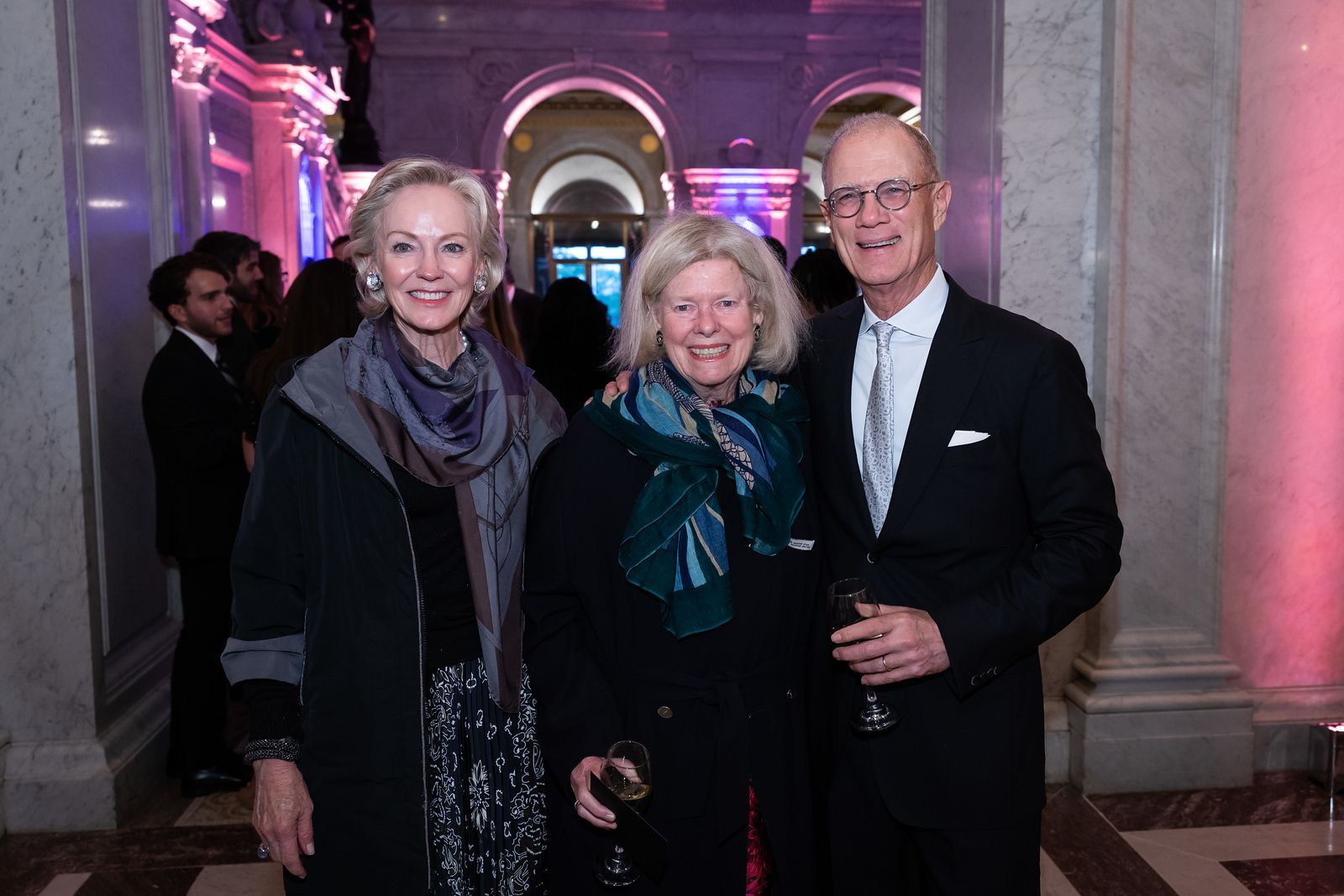 A man and two women are posing for a picture in a hallway.