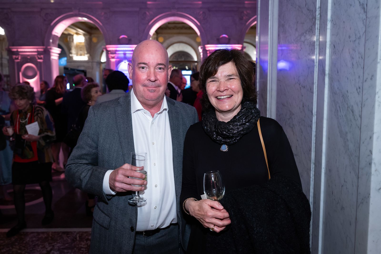A man and a woman are standing next to each other holding wine glasses.