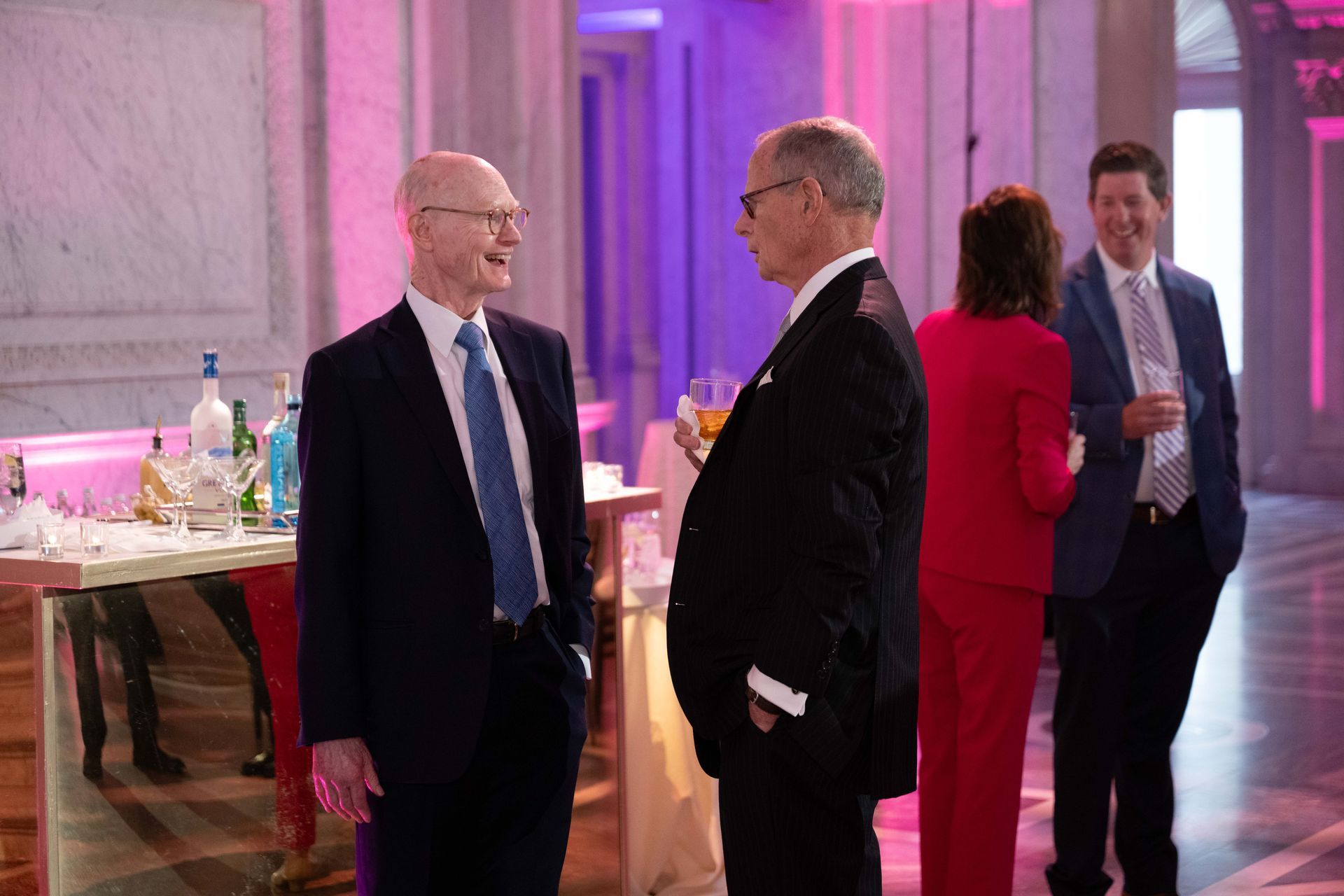 Two men in suits are talking to each other in a room.
