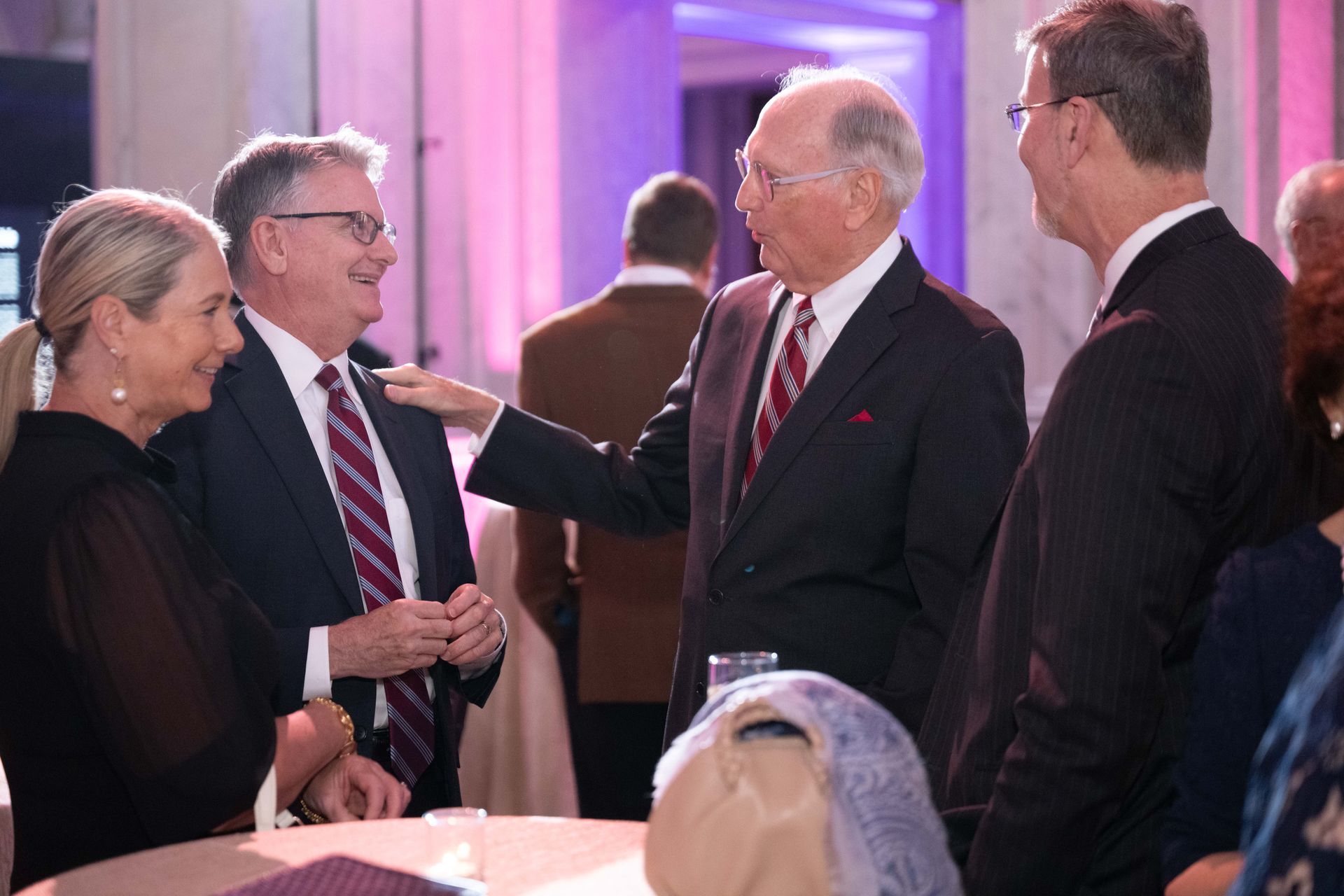 A group of people are standing around a table talking to each other.