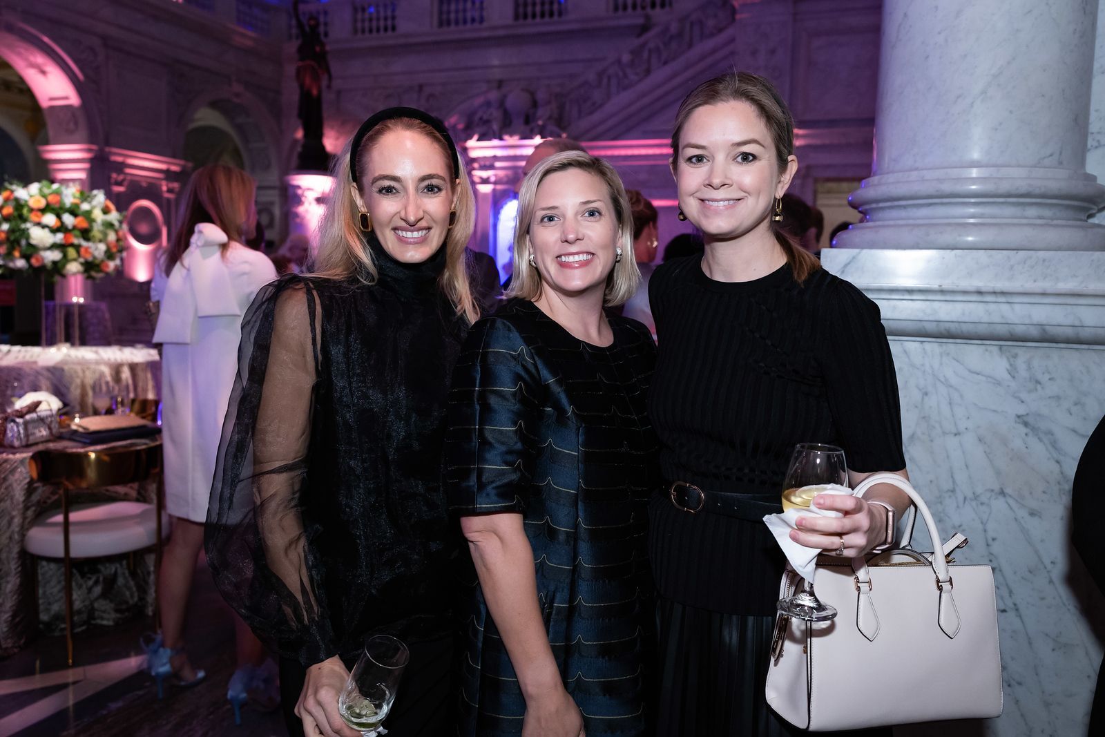 Three women are posing for a picture together at a party.