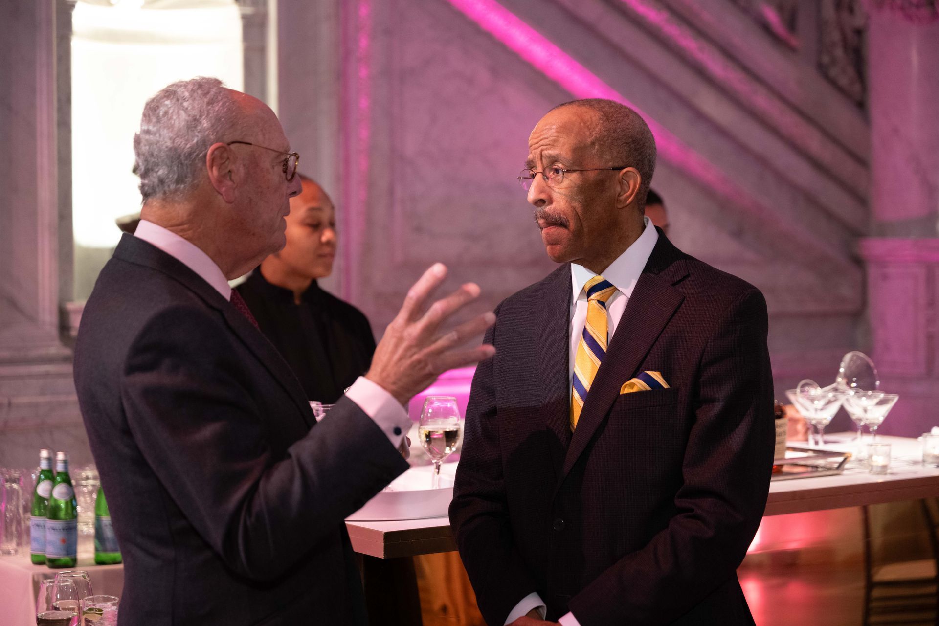 Two men in suits are talking to each other in a room.