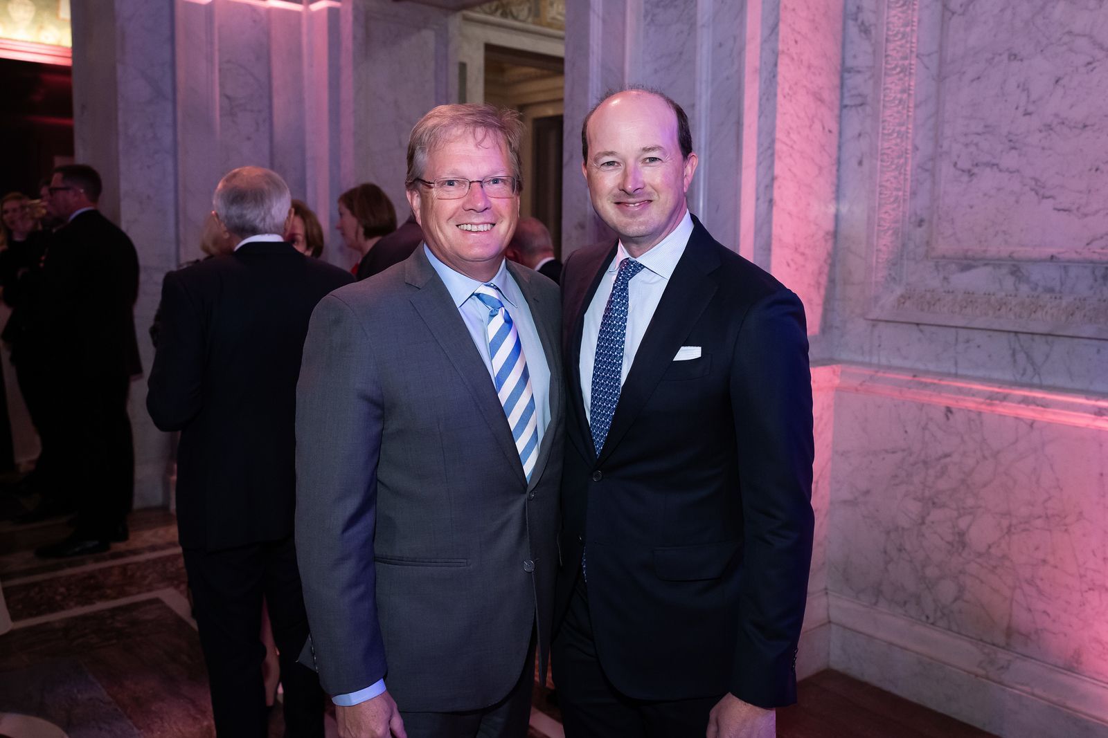 Two men in suits and ties are posing for a picture.