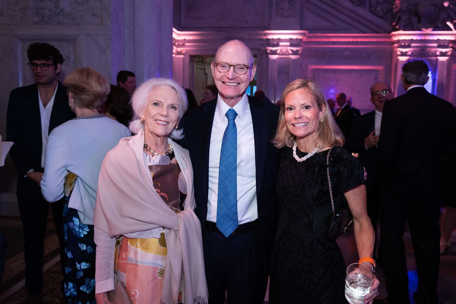 A man and two women are posing for a picture at a party.