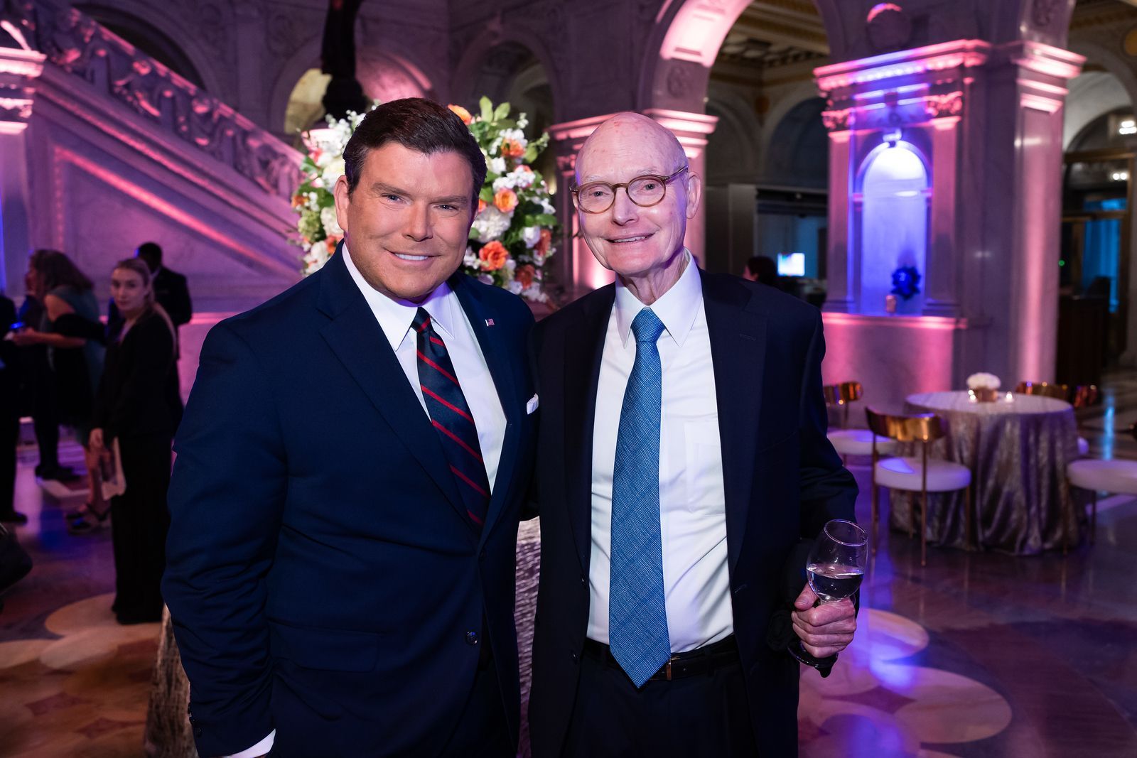 Two men in suits and ties are posing for a picture in a room.