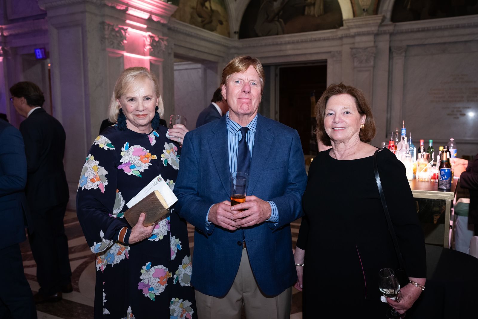 A man and two women are posing for a picture at a party.