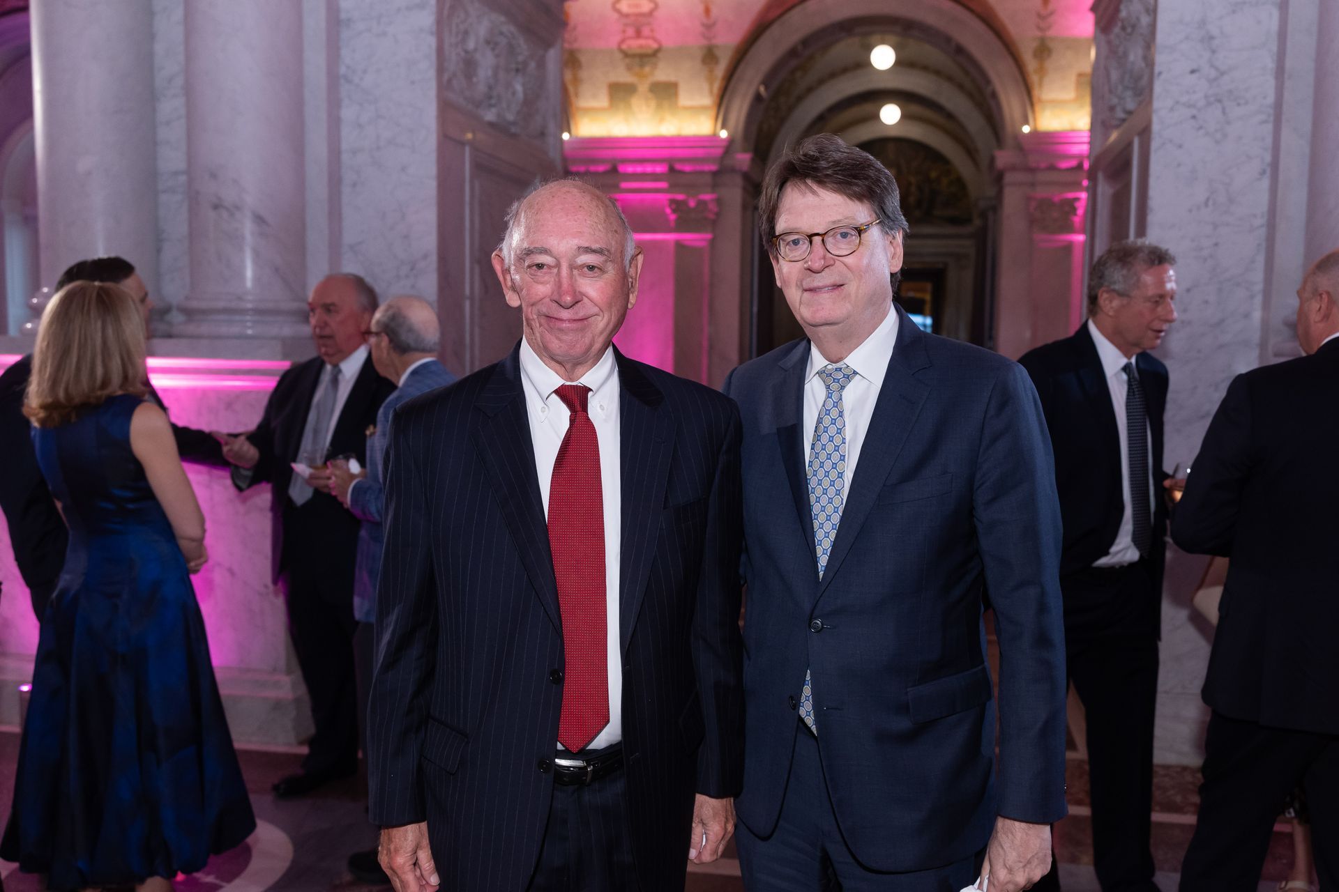 Two men in suits and ties are standing next to each other in a room.