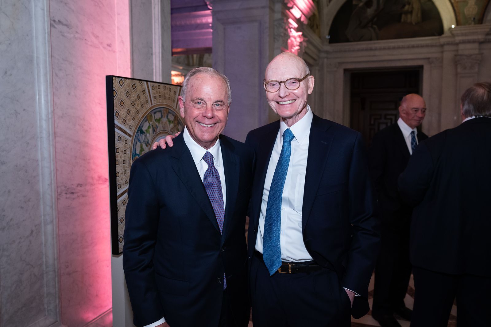 Two men in suits and ties are posing for a picture.
