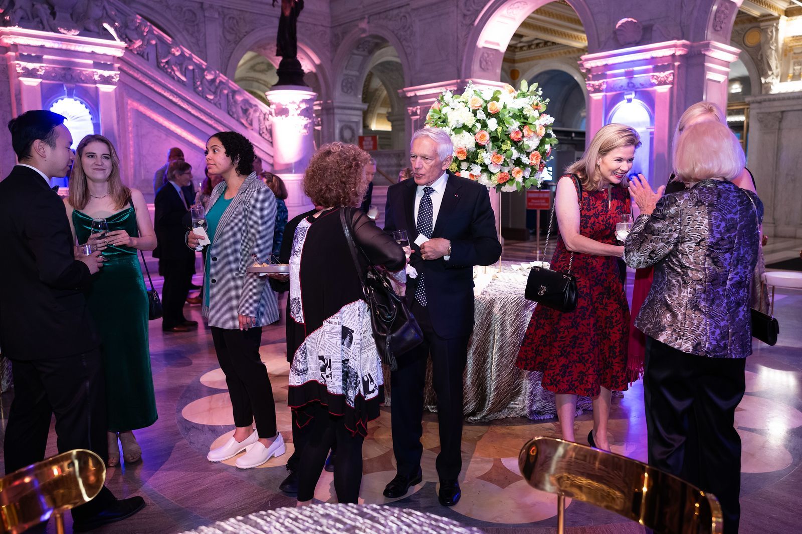 A group of people are standing in a room talking to each other.