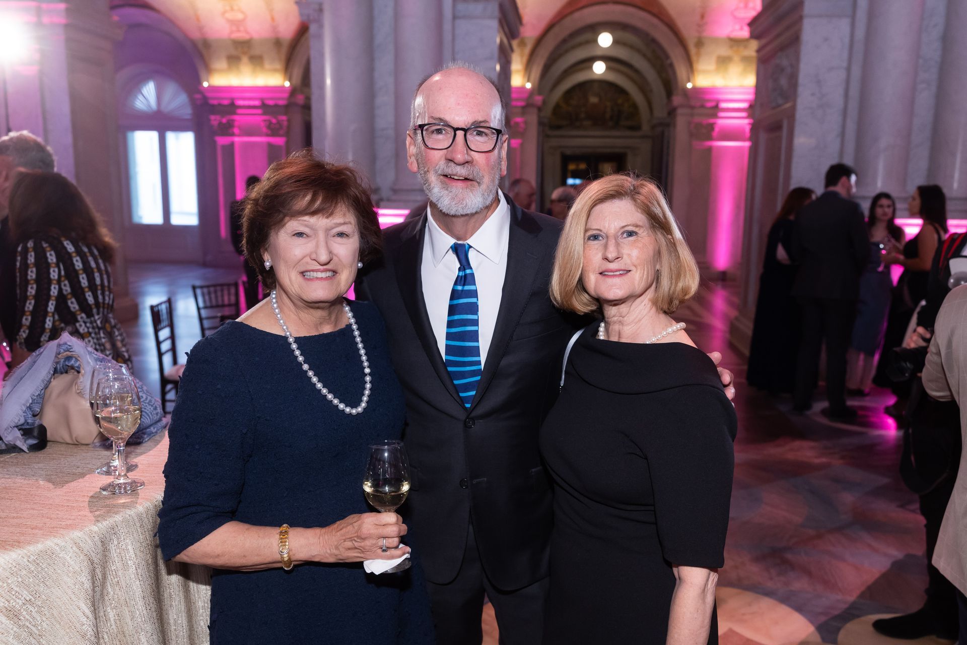 A man and two women are posing for a picture at a party.
