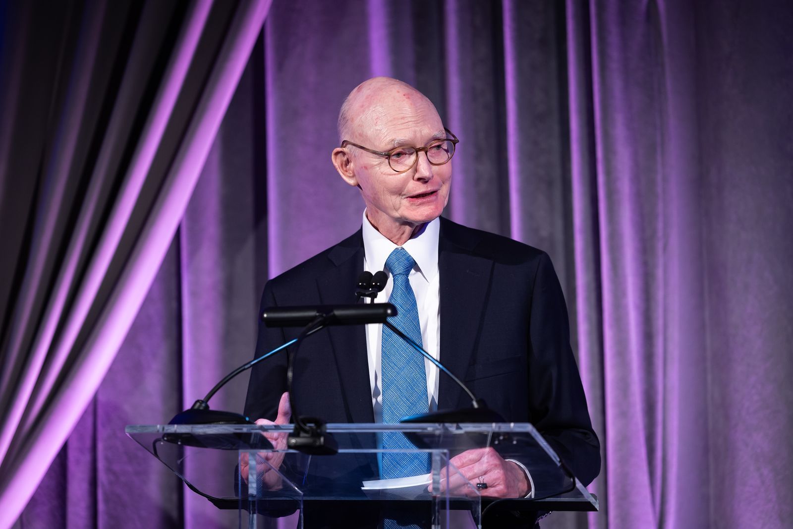 A man in a suit and tie is standing at a podium giving a speech.
