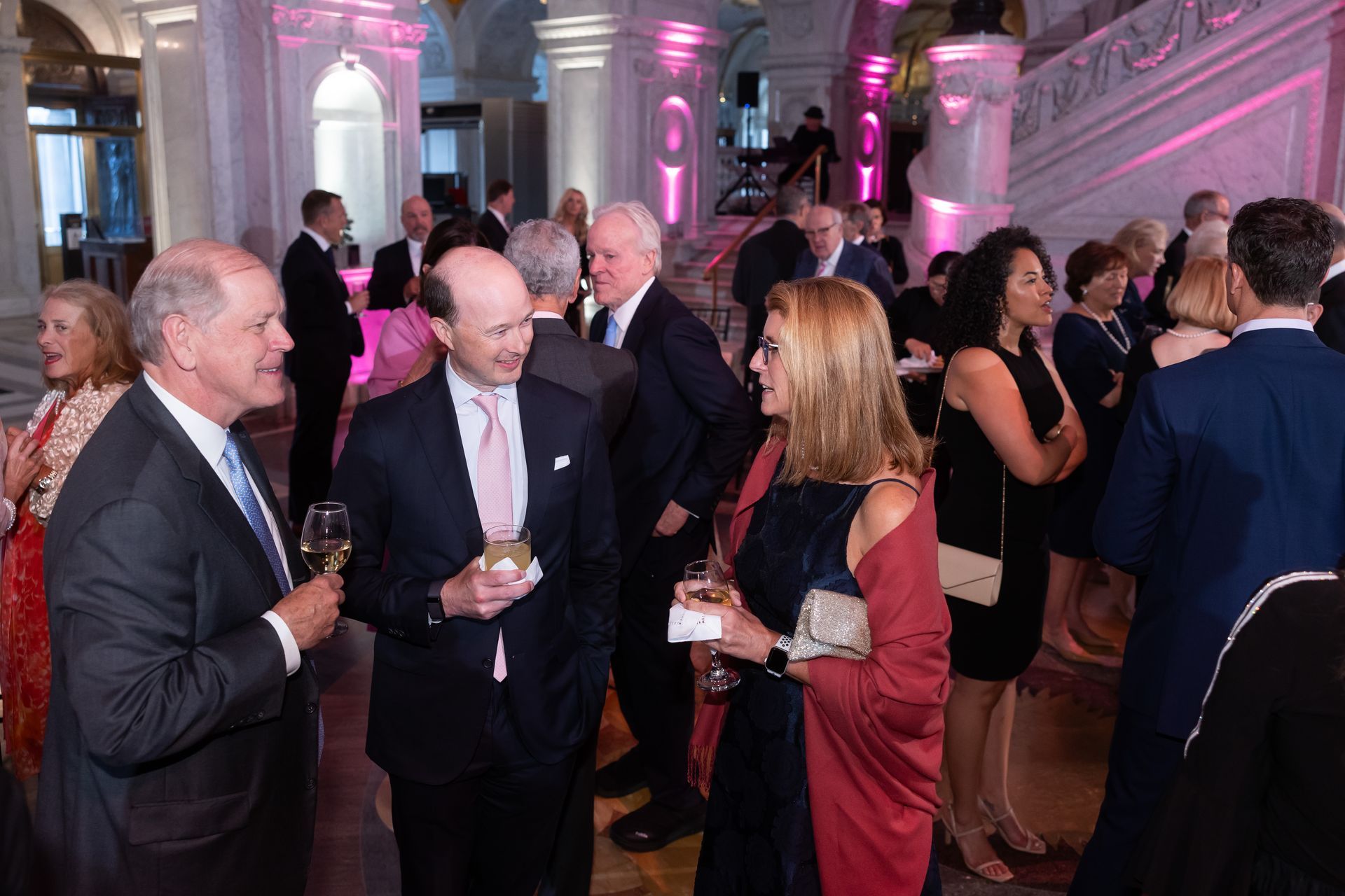 A group of people are standing in a room talking to each other.