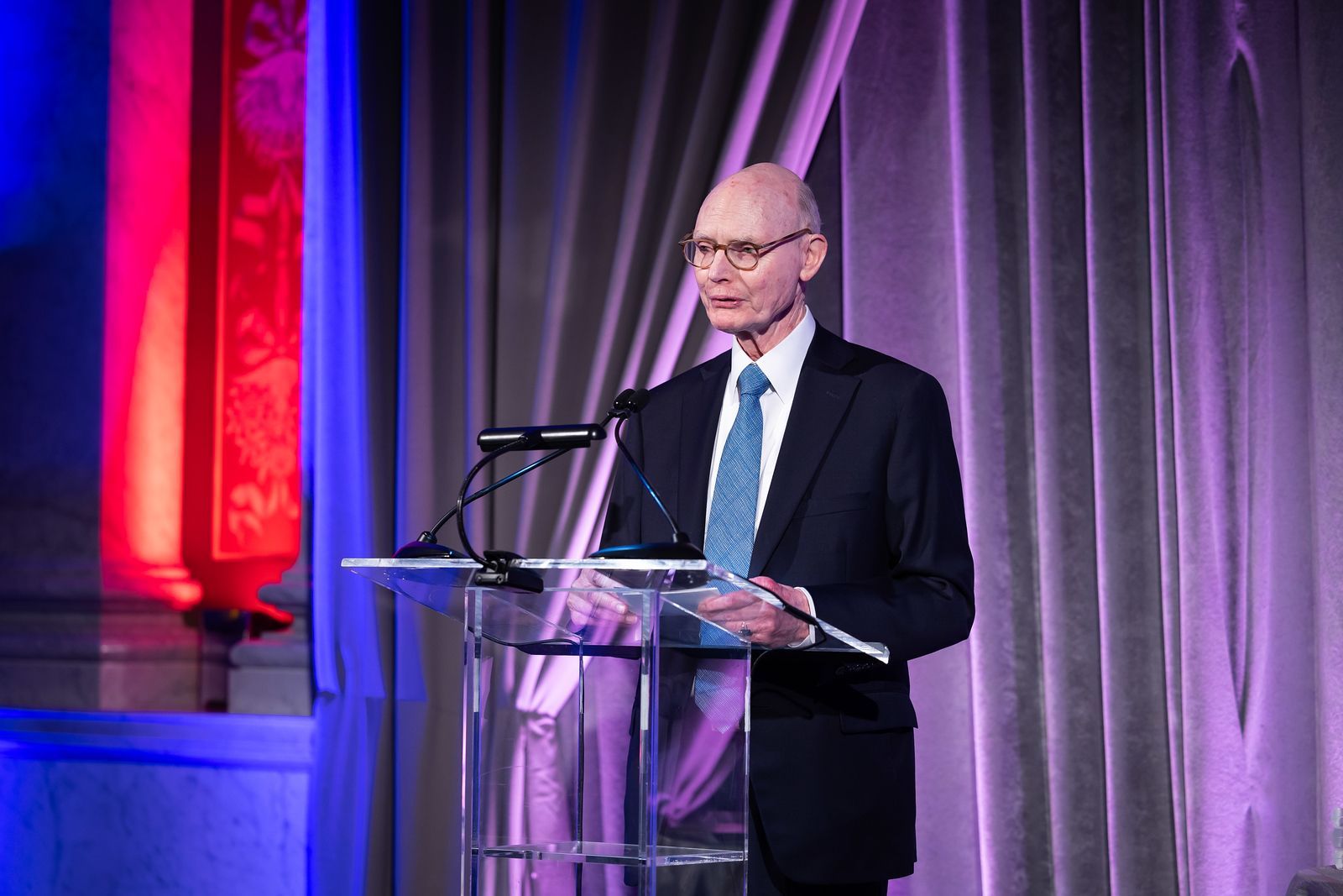 A man in a suit and tie is standing at a podium giving a speech.