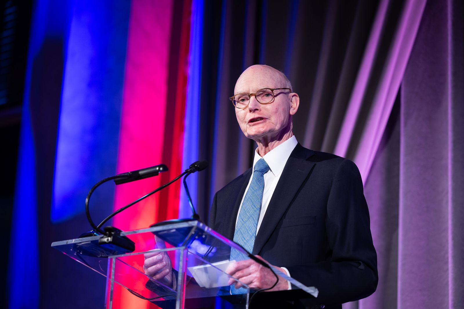 A man in a suit and tie is standing at a podium giving a speech.