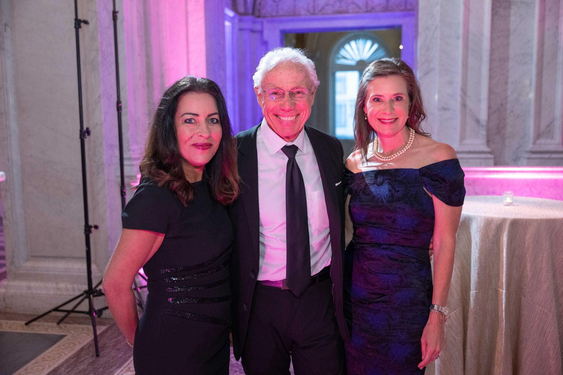 A man and two women are posing for a picture in a room.