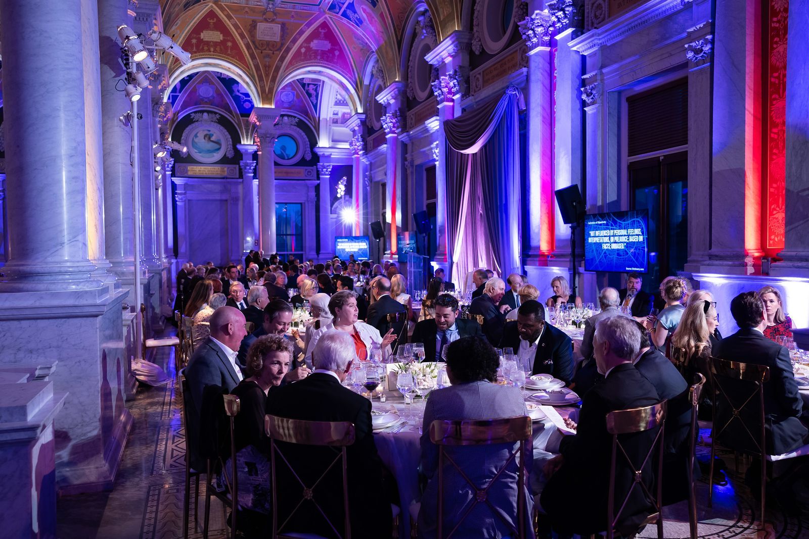 A large group of people are sitting at tables in a large room.