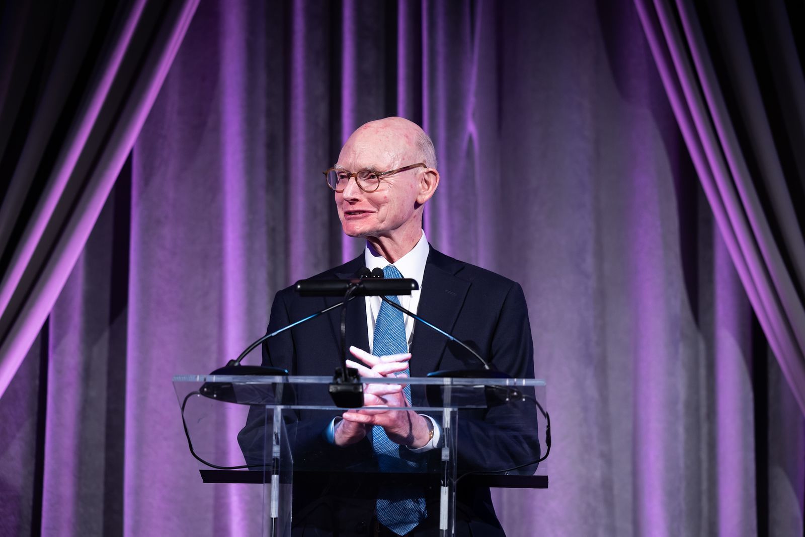 A man in a suit and tie is standing at a podium giving a speech.