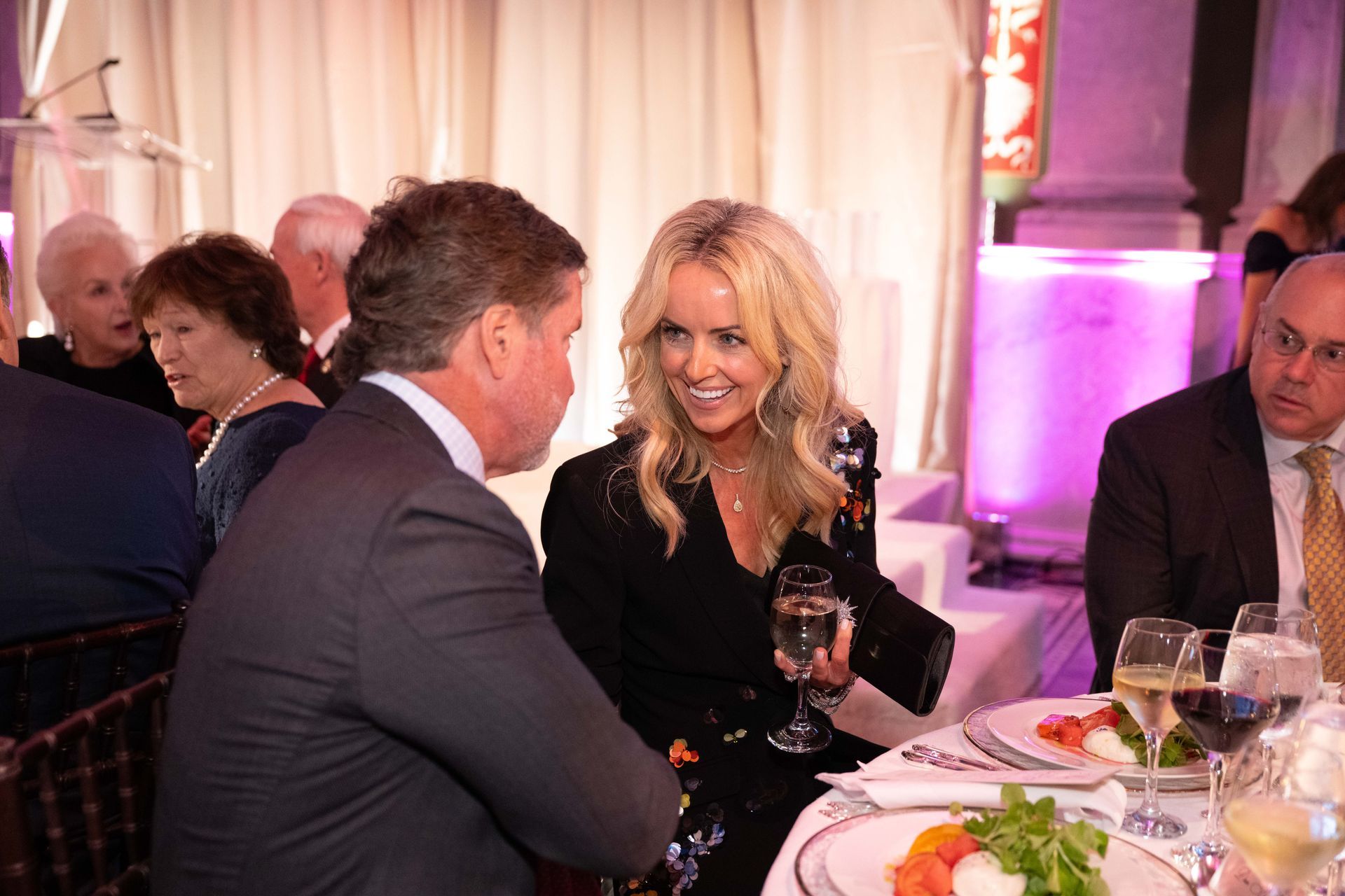 A man and a woman are sitting at a table talking to each other.