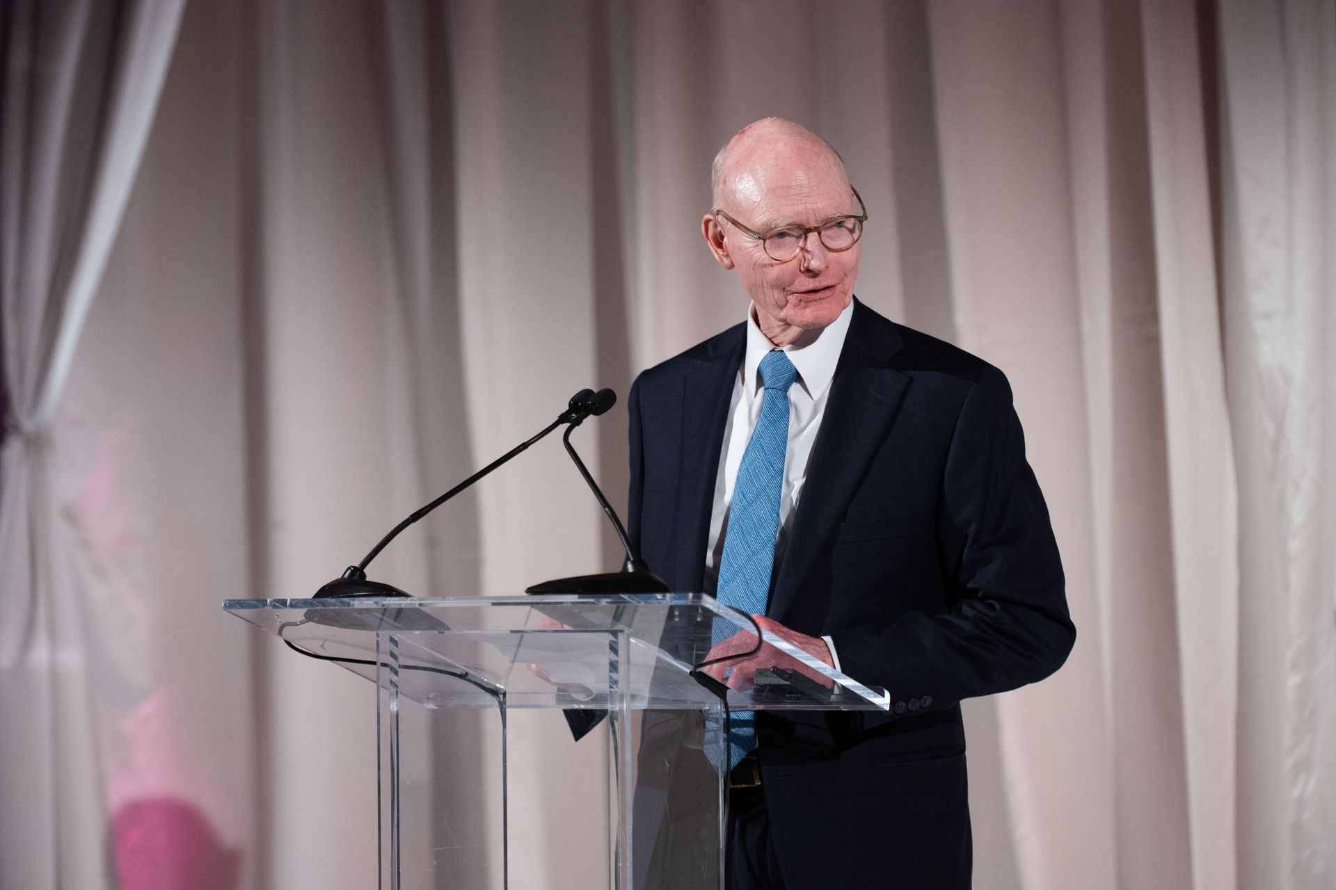 A man in a suit and tie is standing at a podium giving a speech.