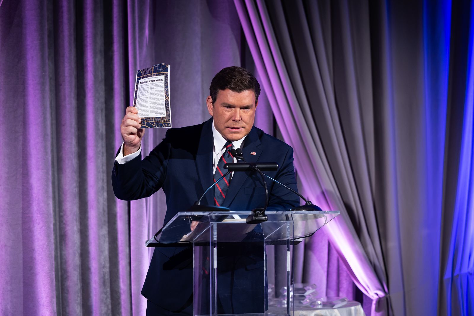 A man in a suit and tie is standing at a podium holding an award.