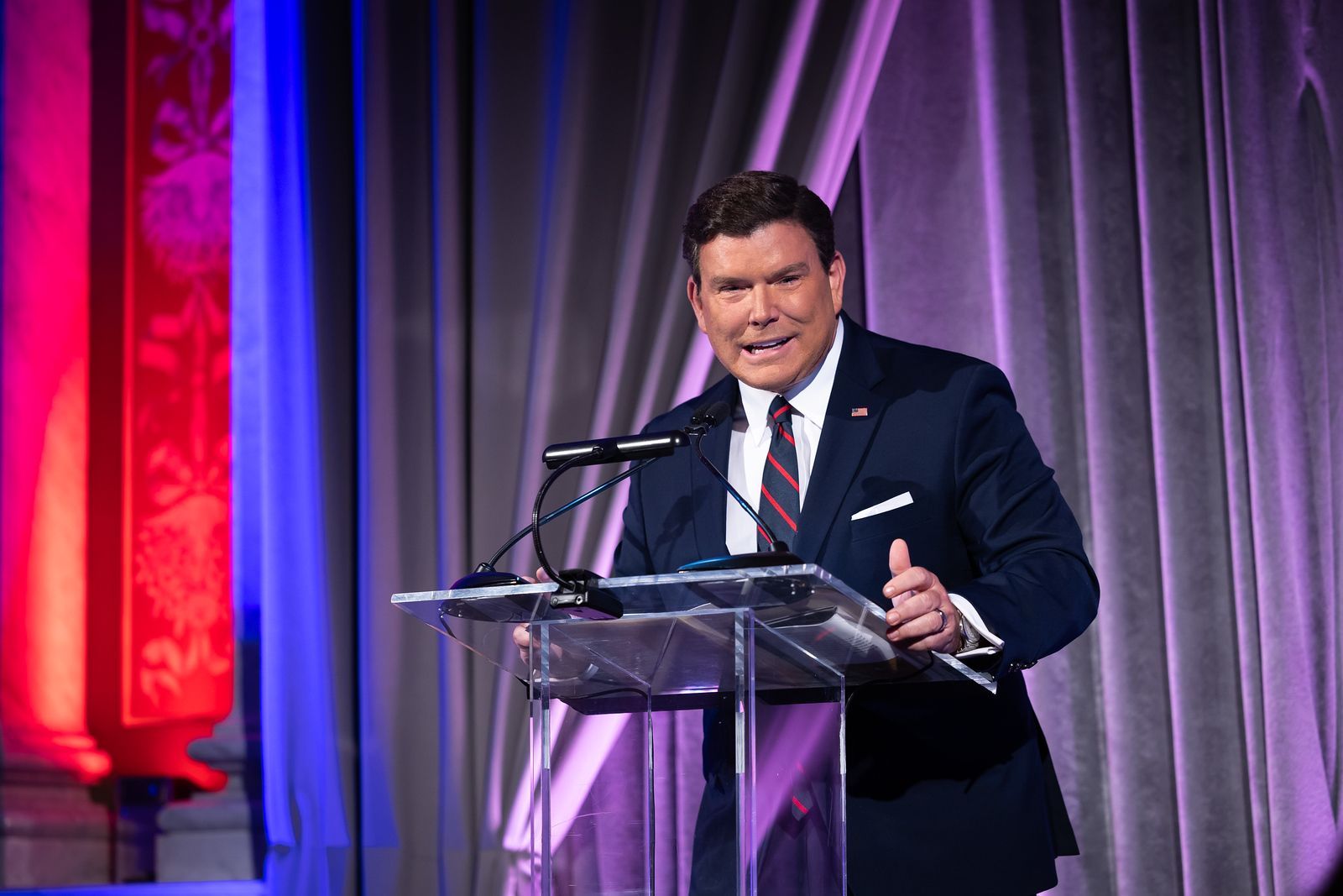 A man in a suit and tie is standing at a podium giving a speech.