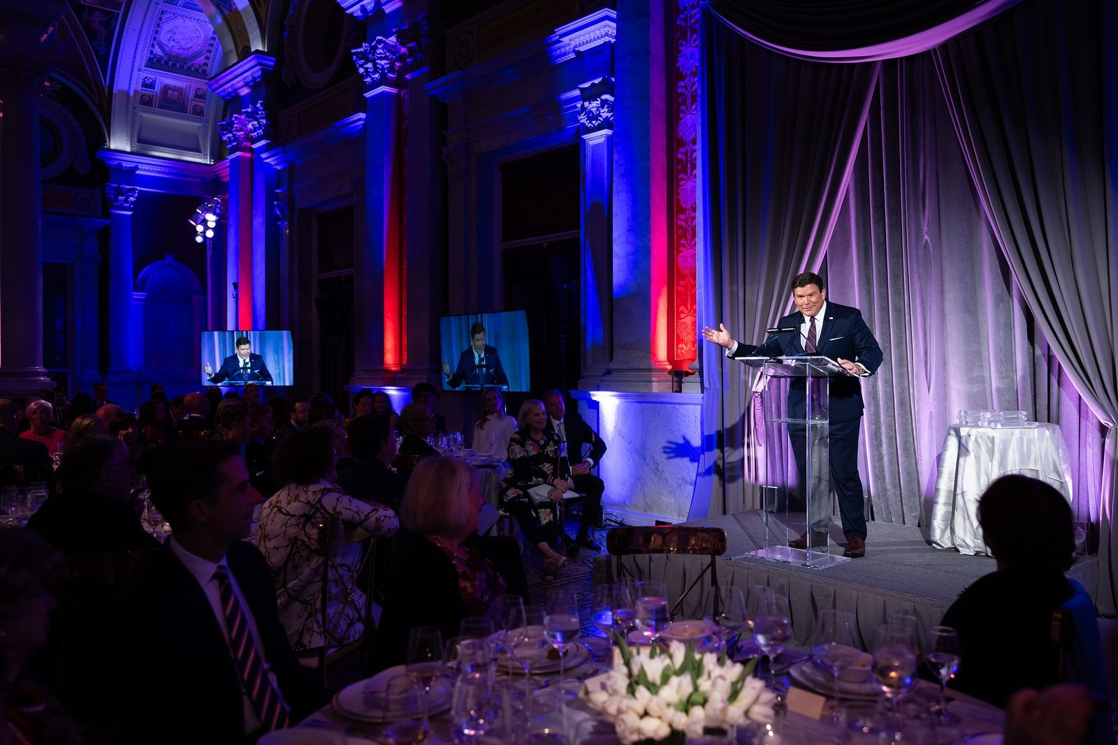 A man is giving a speech at a podium in front of a crowd.