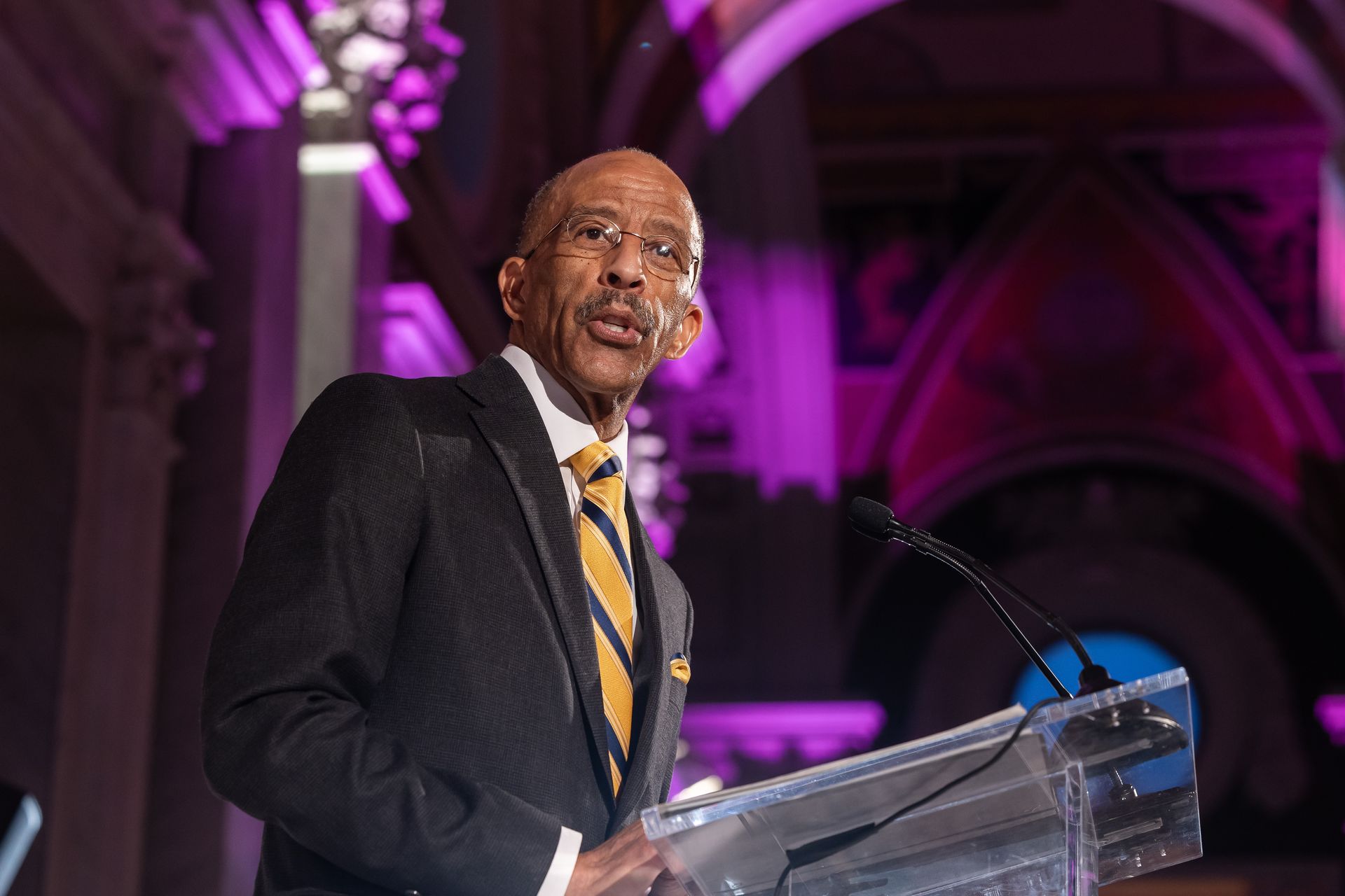 A man in a suit and tie is standing at a podium giving a speech.