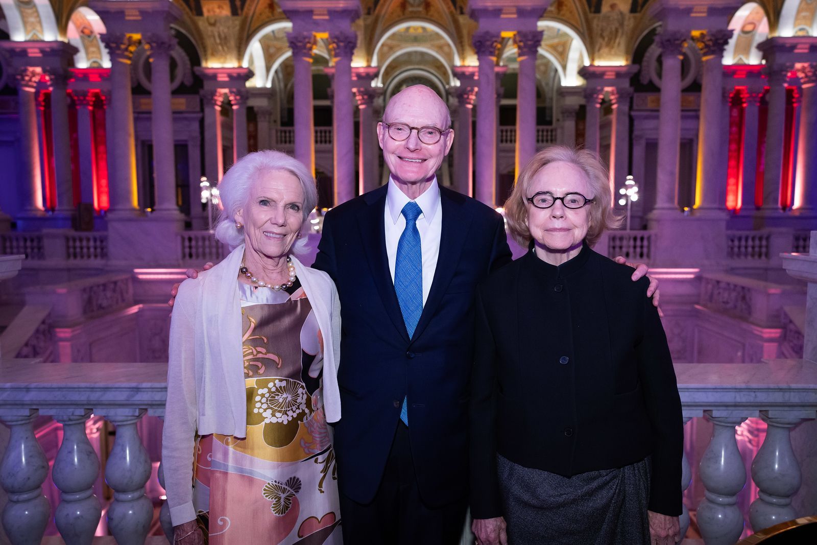 A man and two women are posing for a picture in front of a building.