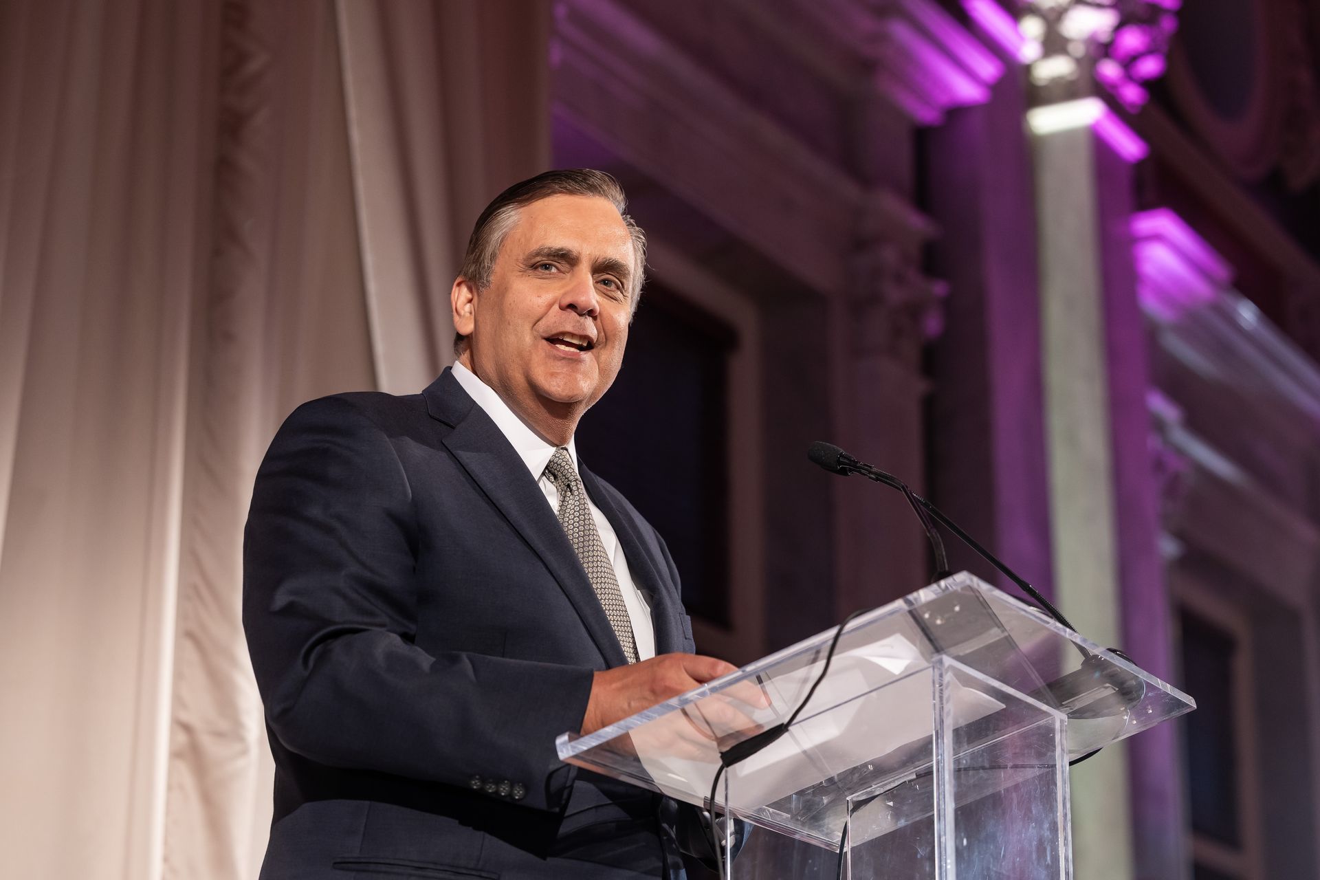 A man in a suit and tie is standing at a podium giving a speech.