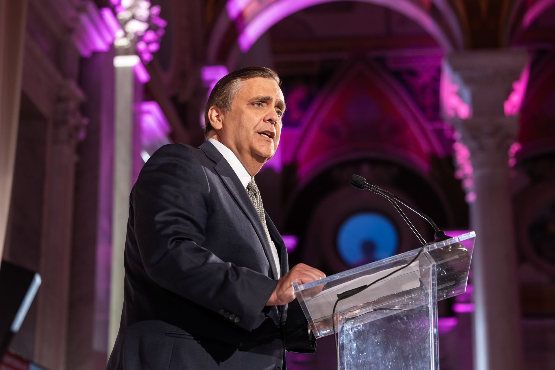 A man in a suit and tie is standing at a podium giving a speech.