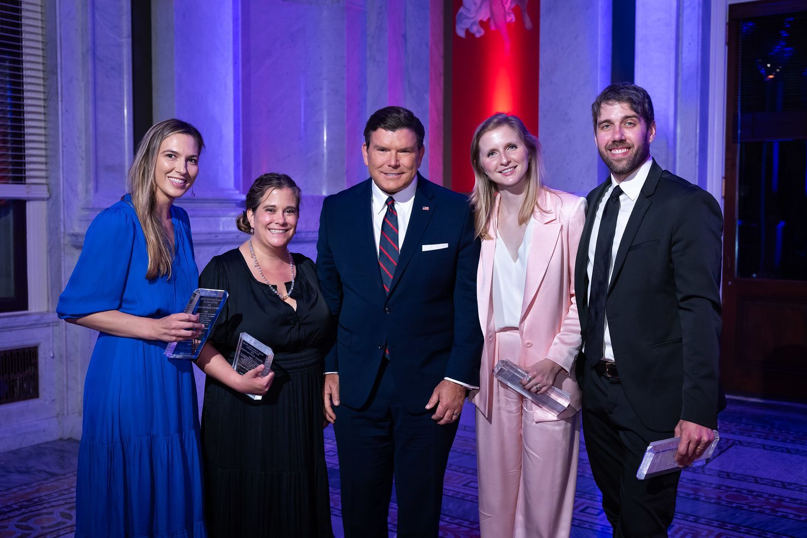 A group of people in suits and dresses are posing for a picture.