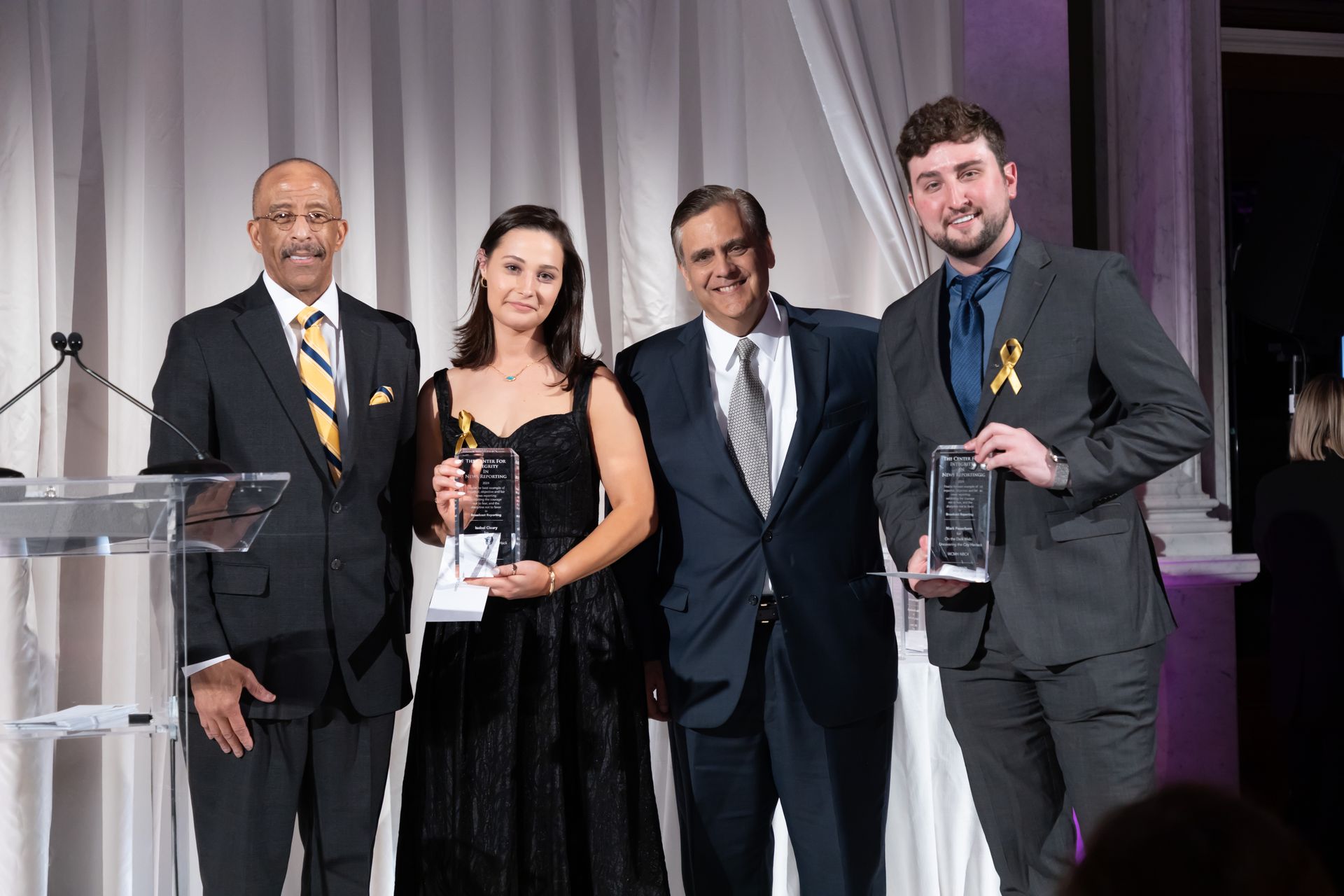 A group of people in suits and ties are standing next to each other holding awards.