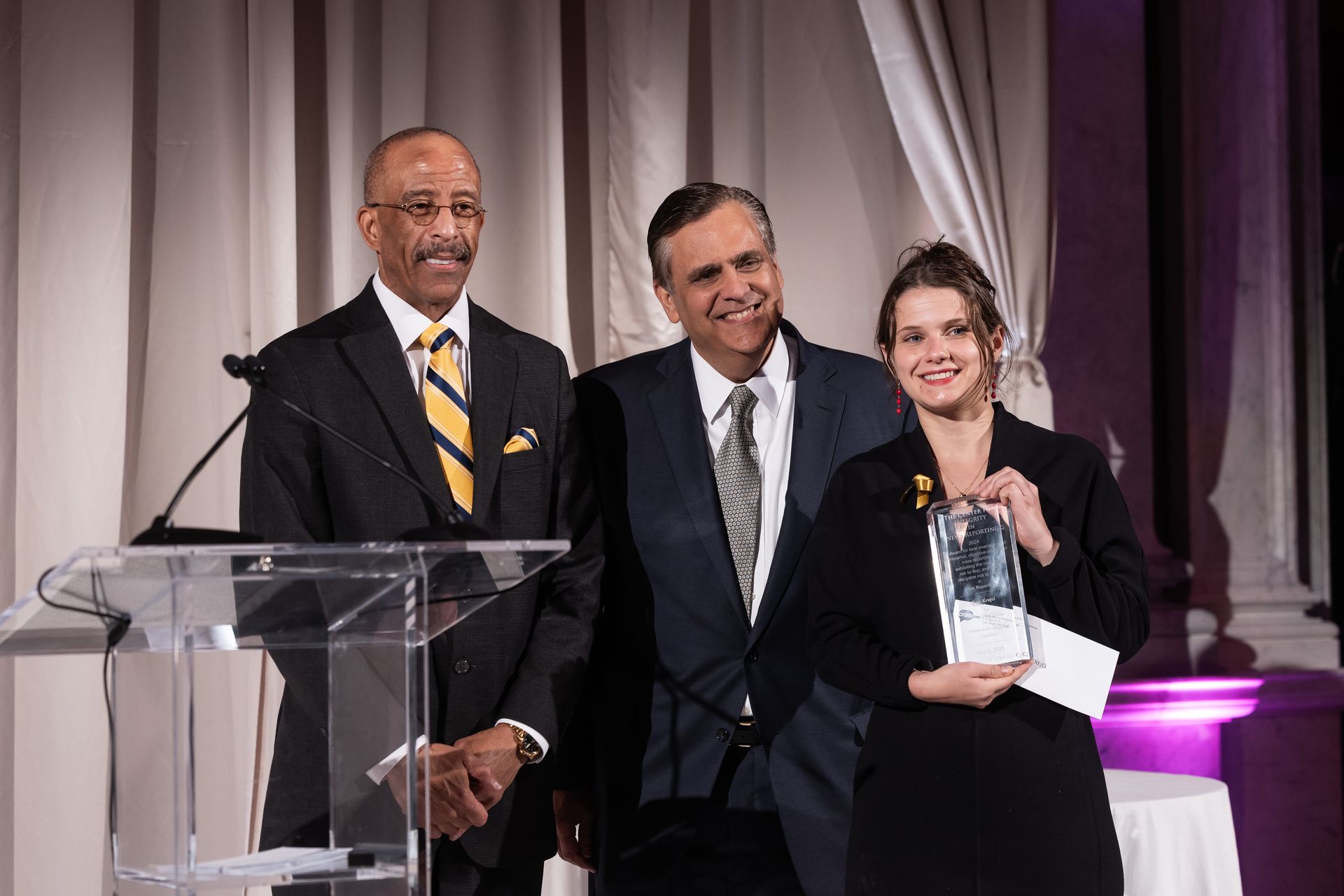 A man in a suit and tie is standing next to a woman holding an award.