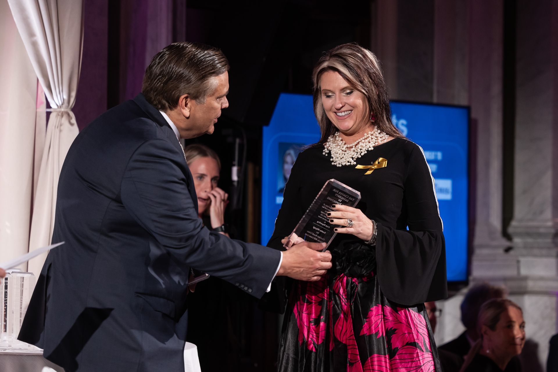 A man in a suit is shaking hands with a woman in a pink and black dress.