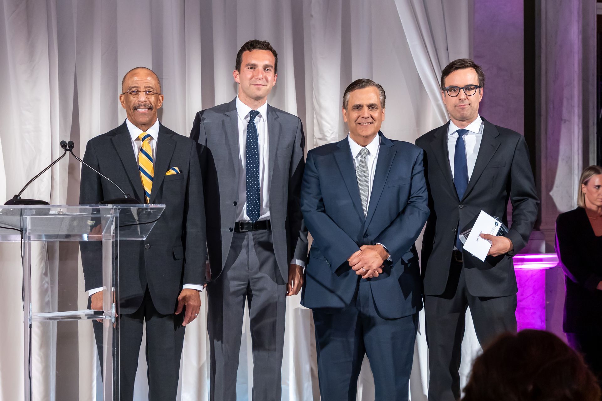 A group of men in suits and ties are standing in front of a podium.