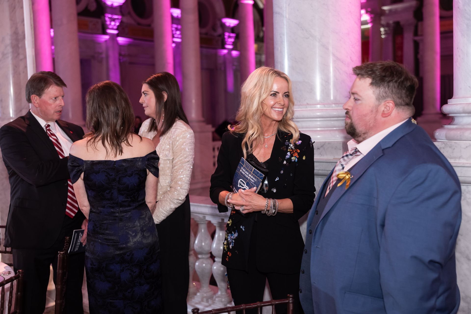 A group of people are standing in a room talking to each other.