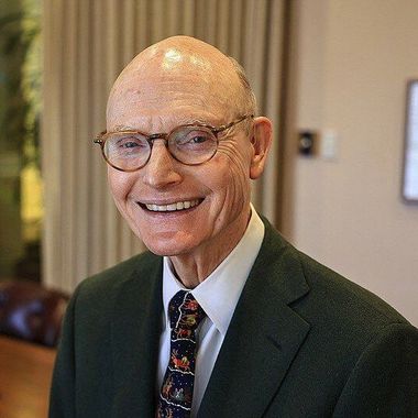 A bald man wearing glasses and a suit and tie is smiling.