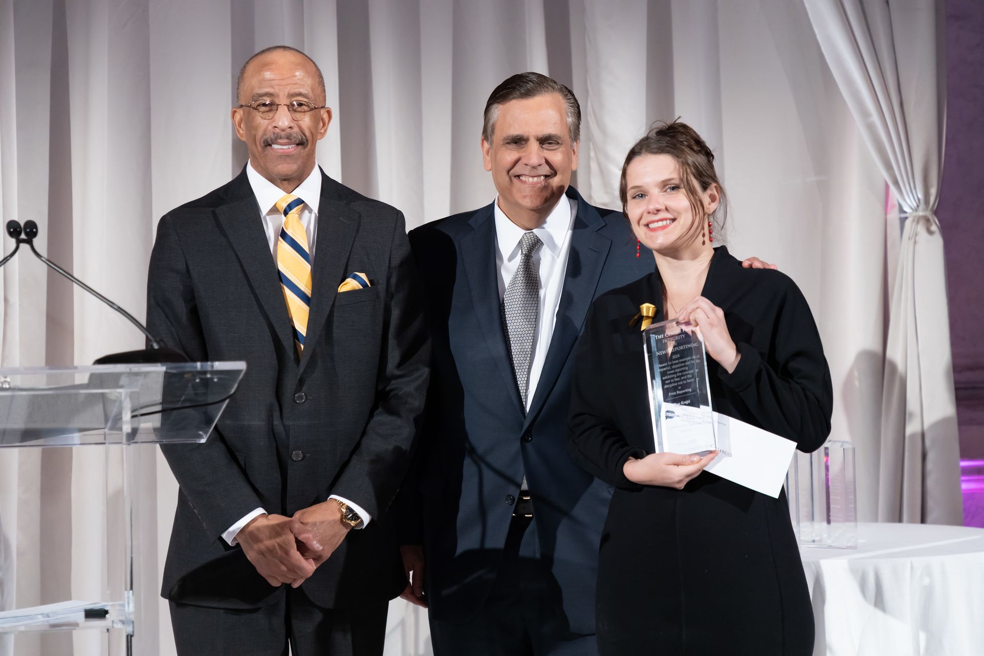 Two men and a woman are standing next to each other in front of a podium.